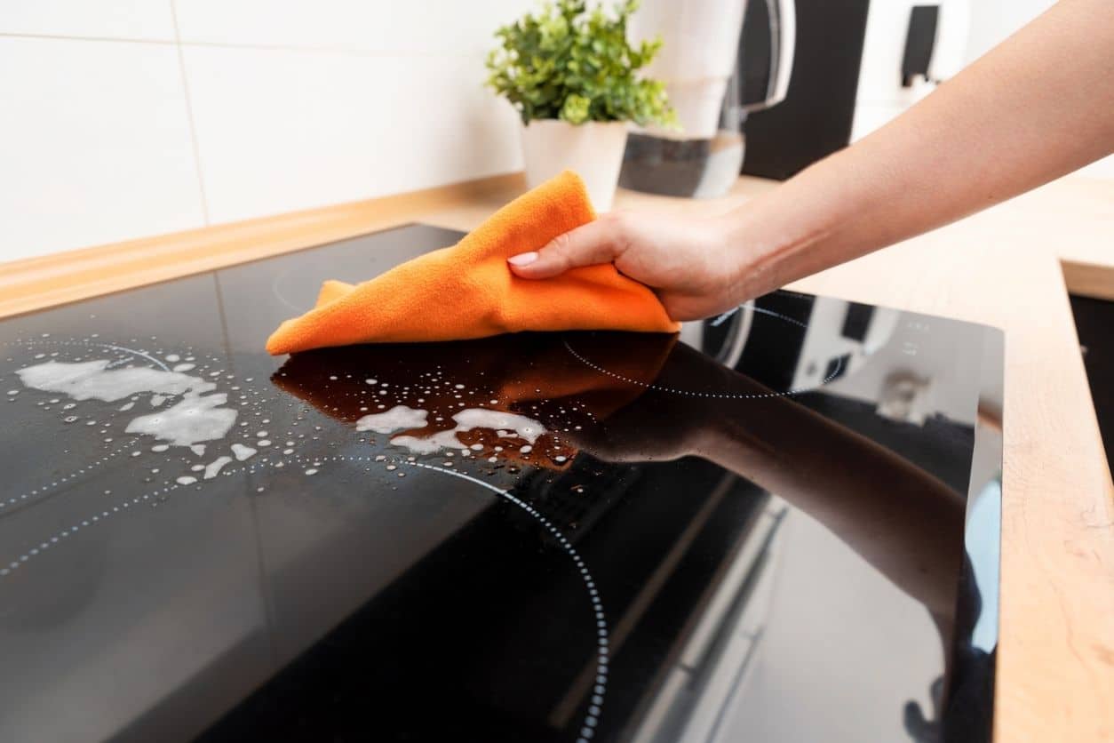 Woman cleaning induction stove. Modern kitchen with induction hob.