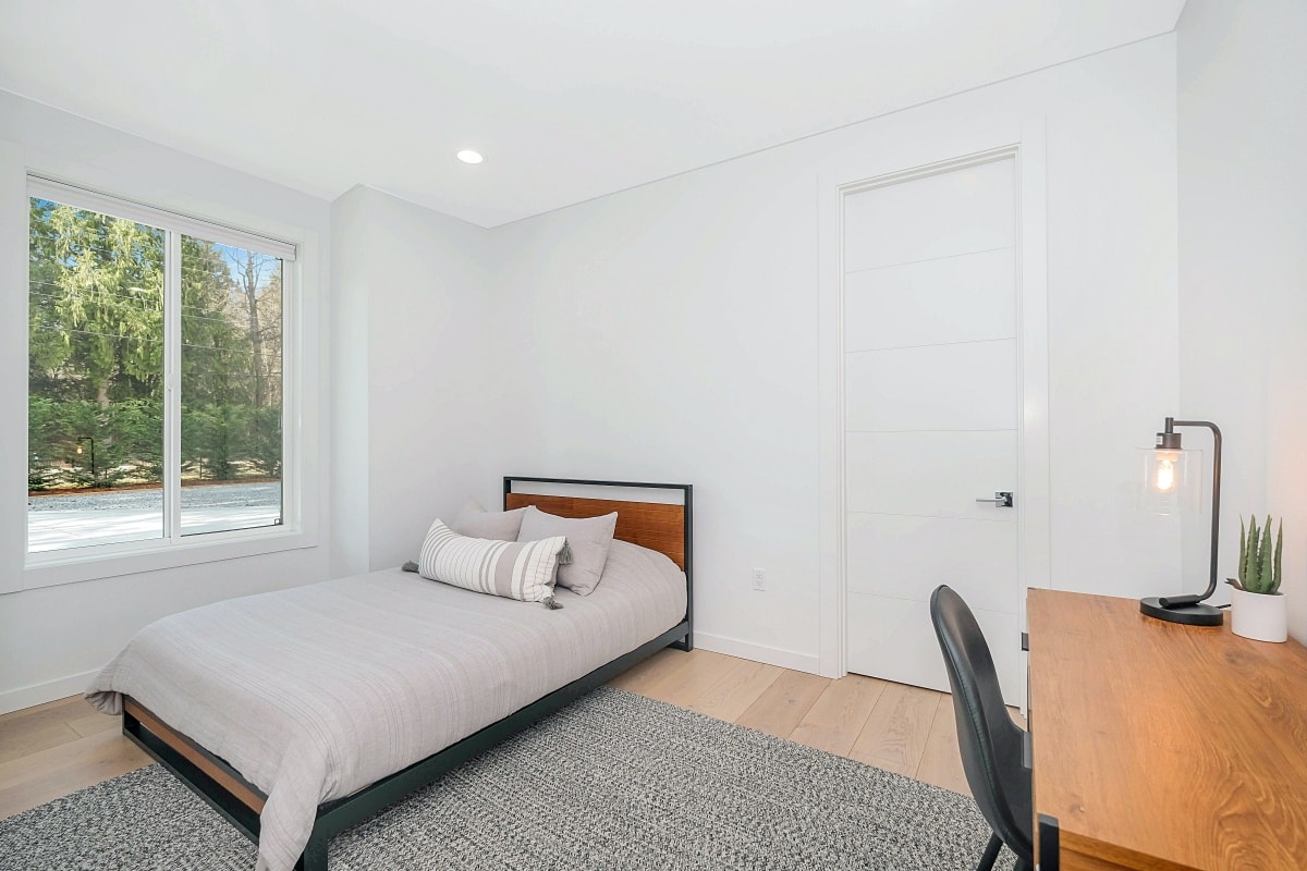 Bedroom with white walls, bed, and study table