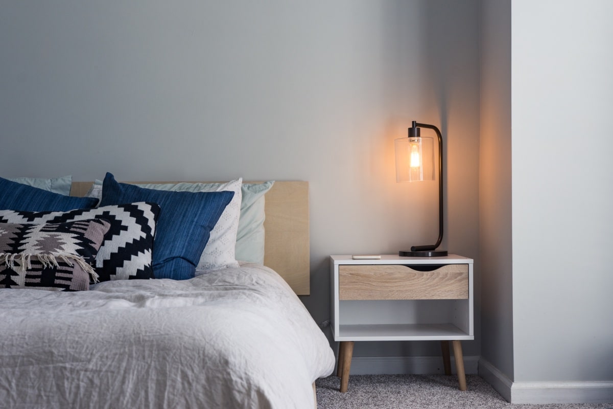 Bedroom with gray walls, bed, night stand, and lamp