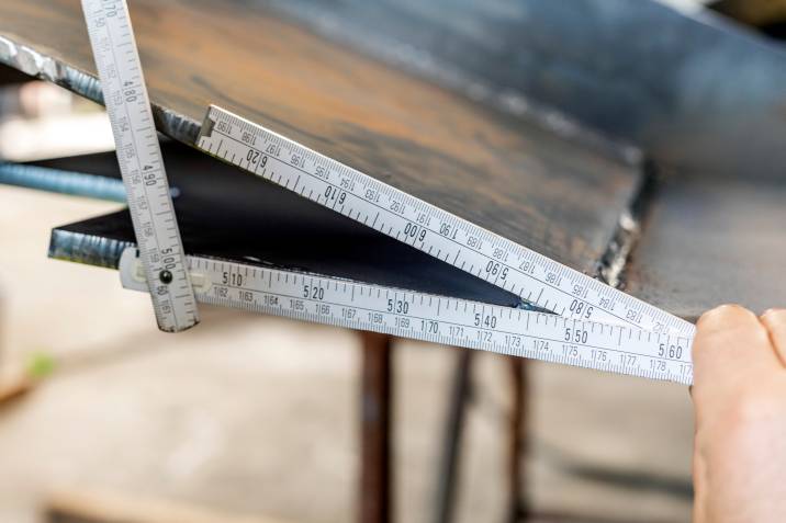 A handyman measuring the angle of a steel part with an angle finder, finder protector of a wooden meter