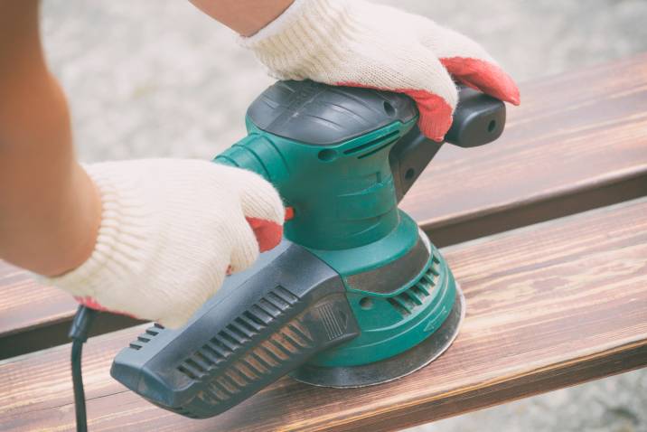 Sanding wood with orbital sander outdoors
