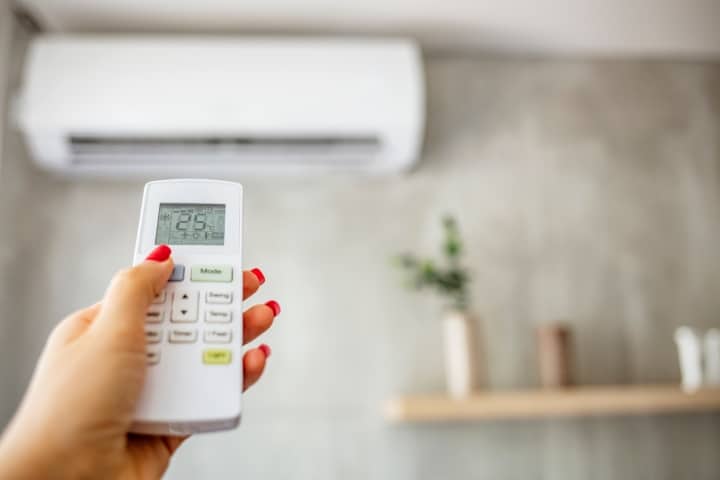 a woman adjusting the temperature of her air conditioning unit