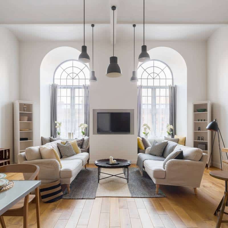 Two big arch windows in living room, partially covered by curtains. Contemporary TV living room with two sofas 