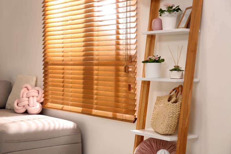 faux wood blinds rolled down, stylish room with wooden ladder against white wall