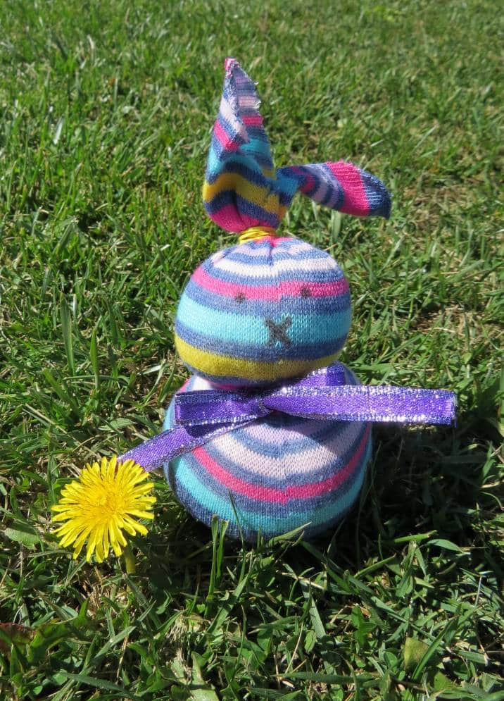 Sock bunny with dandelion on grass