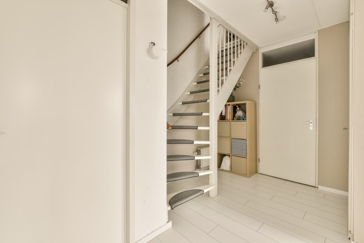 a white room with stairs and shelves on the wall next to an open door