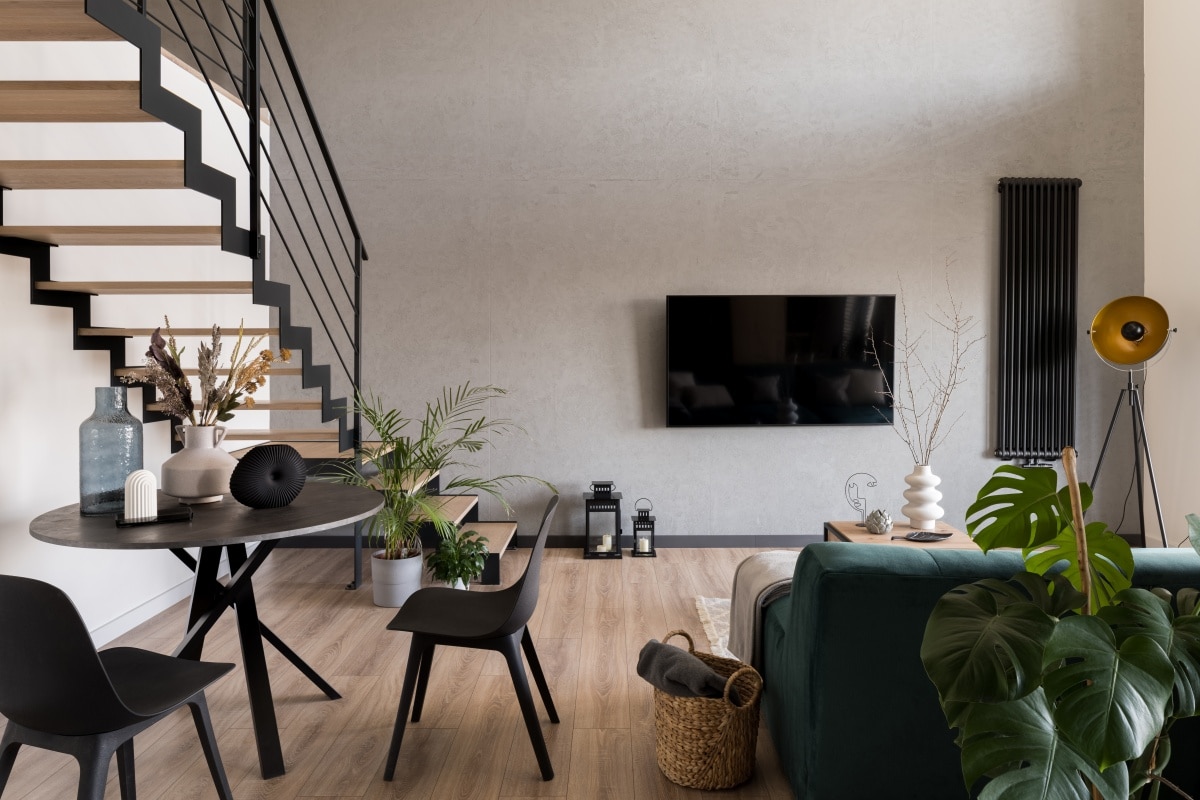 Stylish decorated living room with stairs, big tv screen, cozy sofa and small dining table