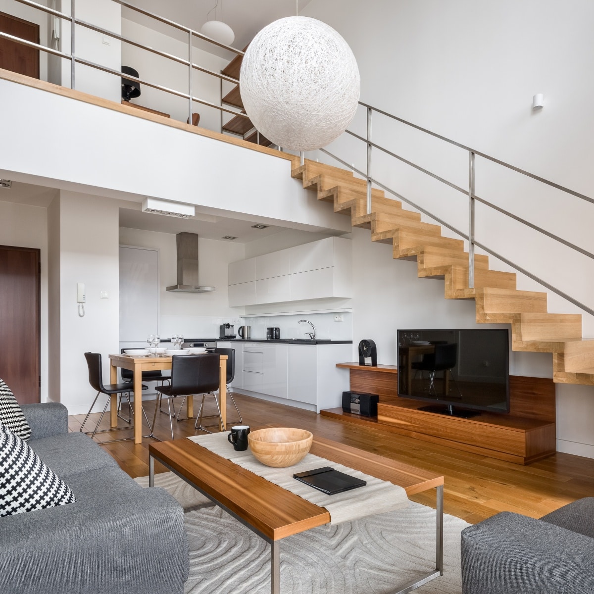 Modern two floor apartment with wooden stairs and living room with tv open to kitchen