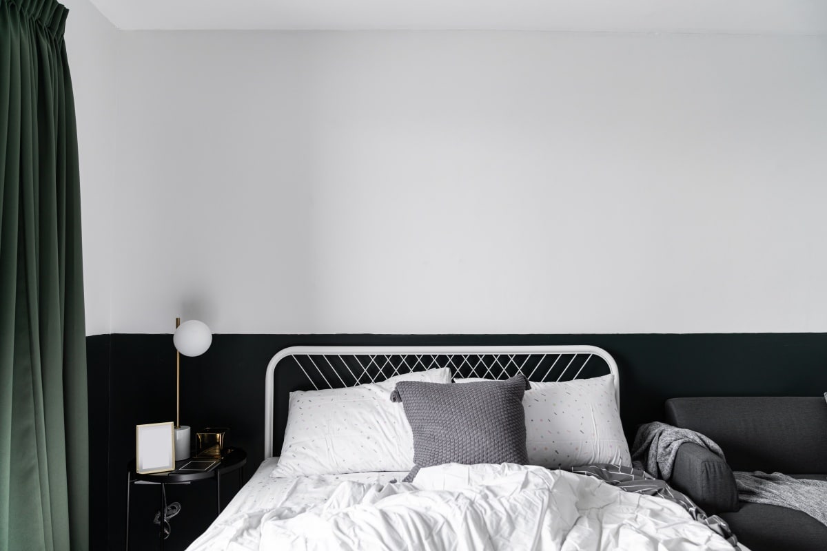 Stylish two tone black and white bedroom corner with decorative frame and plant