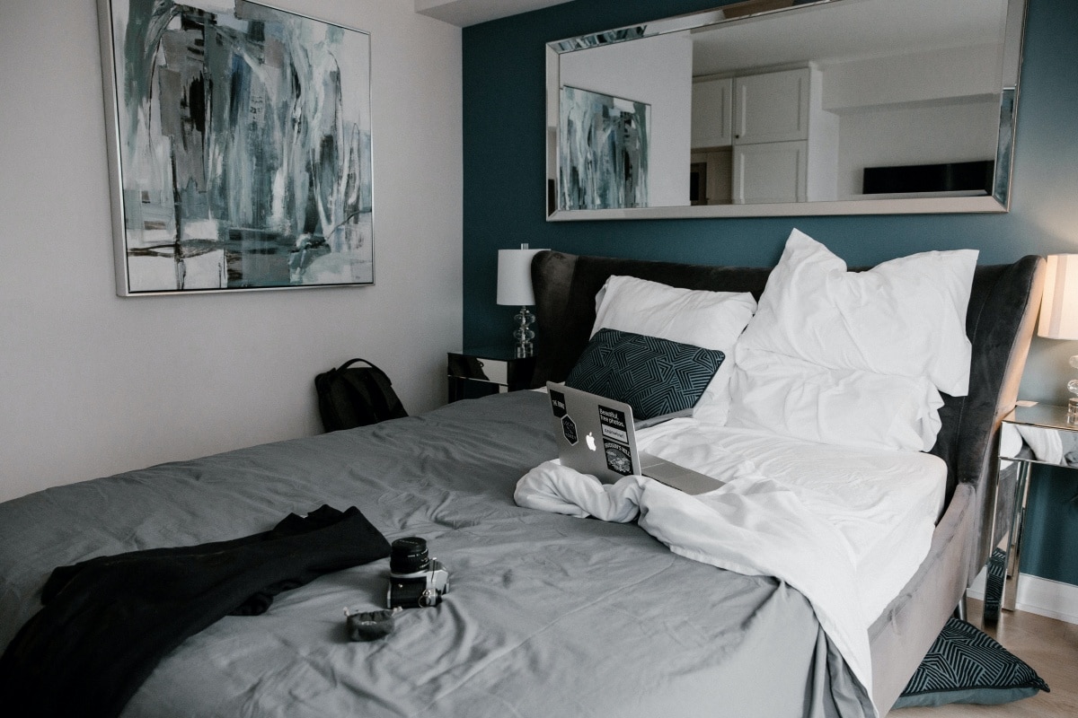 laptop and camera on grey and white bed