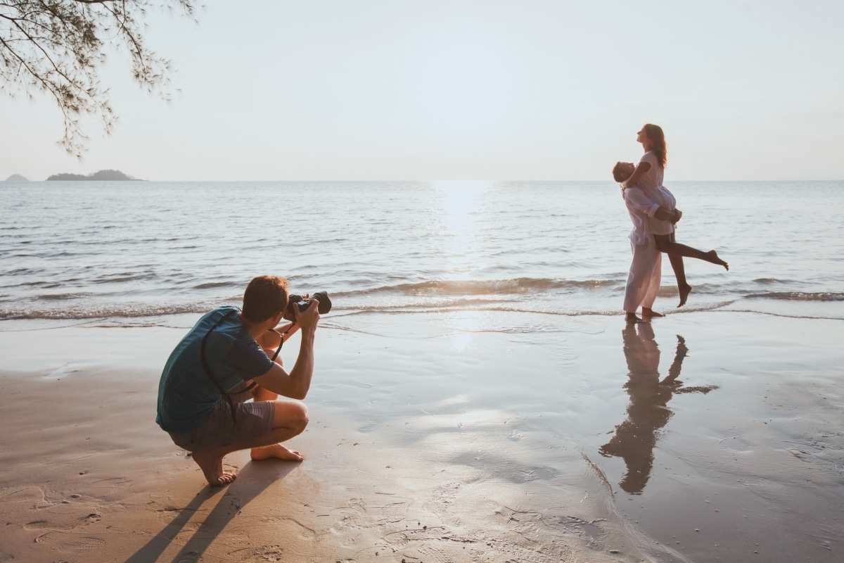 An engagement photographer taking photos of an engaged couple outdoors.