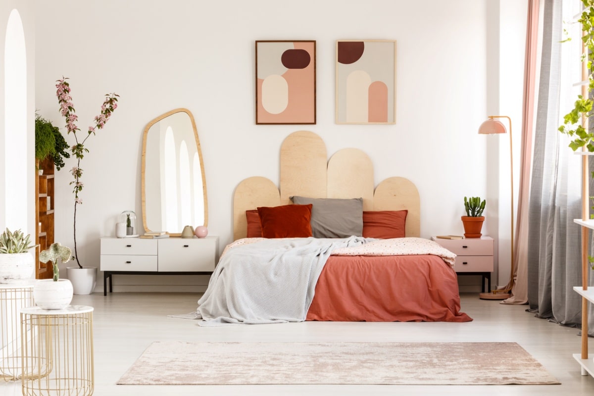 Modern posters above bed with headboard in pastel bedroom interior with mirror