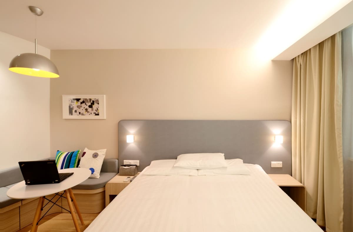 Grey headboard with built-in light on both sides of a white bedspread