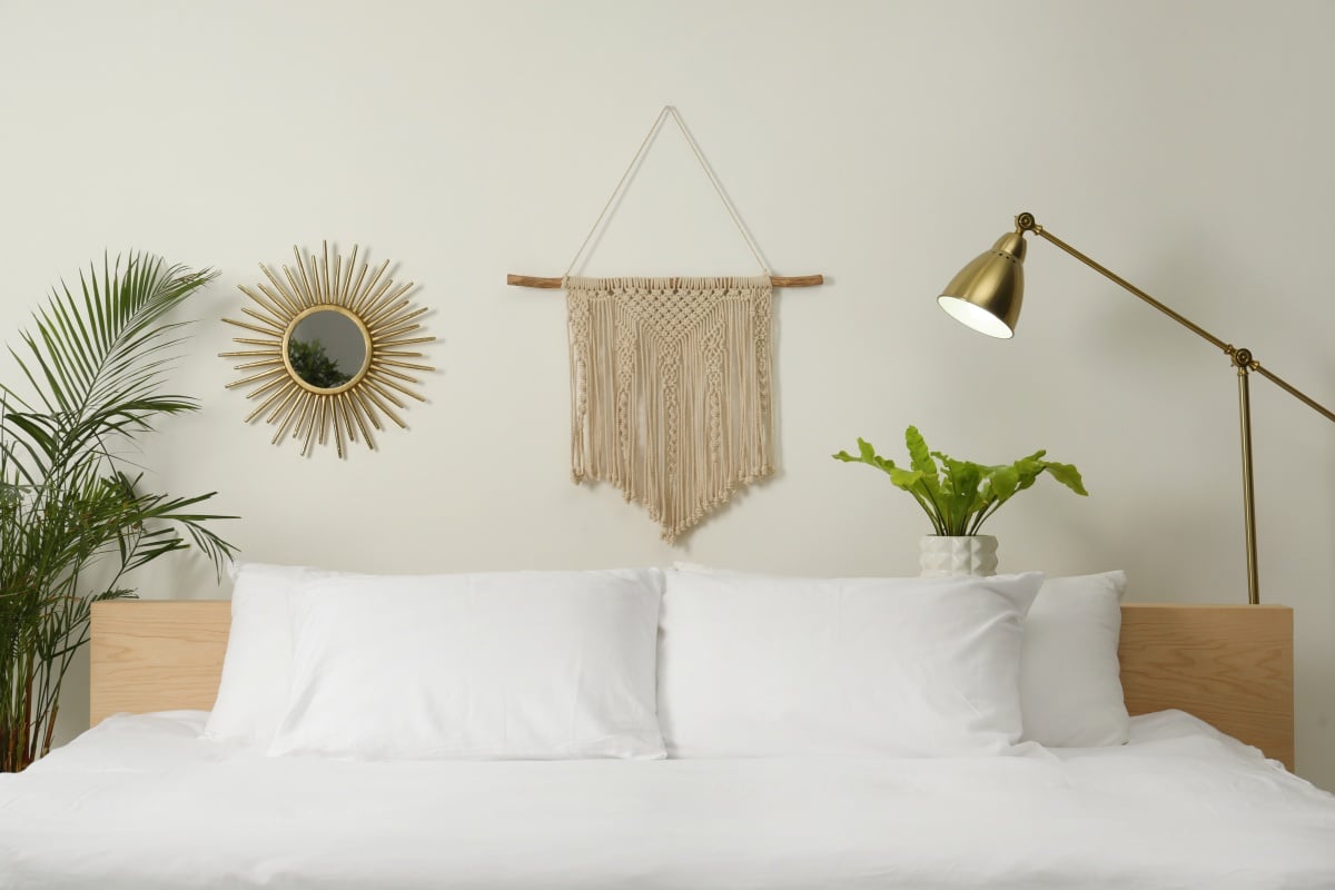 Stylish macrame hanging on white wall in bedroom