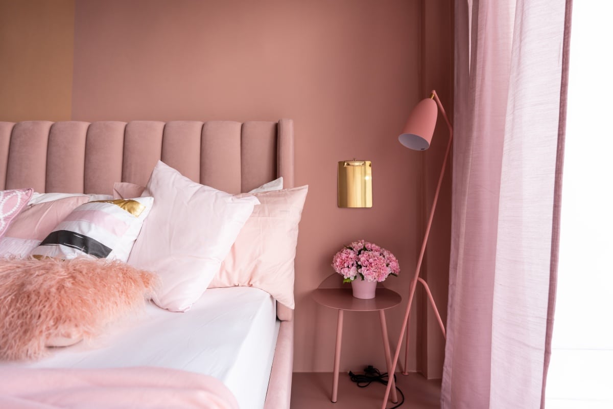 Cozy Pink Bedroom corner with baby pink velvet fabric bed decorated by blanket, pillows and pink floor lamp with two-tone pink painted wall