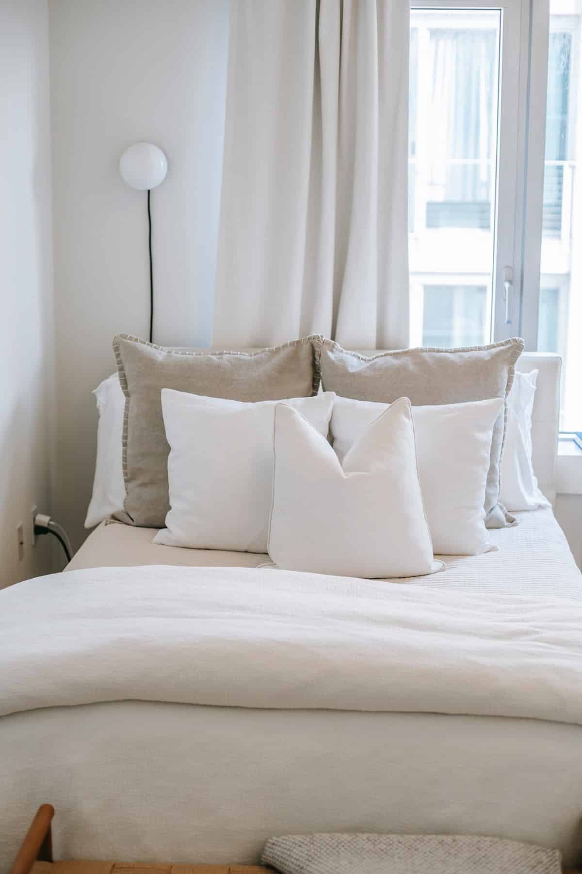 Cosy bed with pillows near window in house