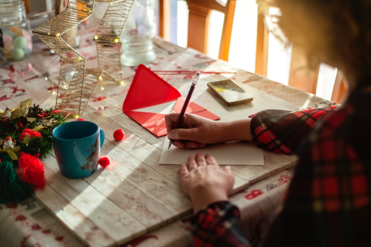 A woman writing a card on a wooden table