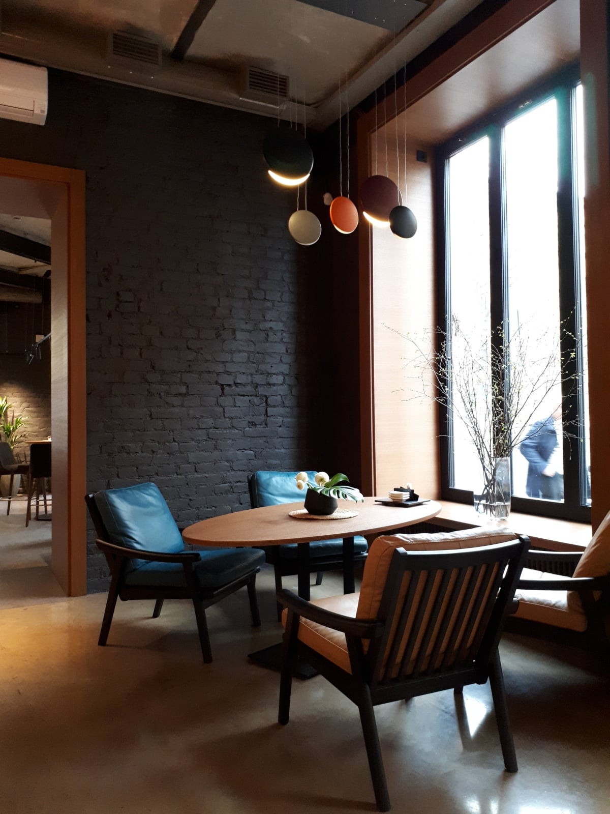 Empty chairs and table in front of a tall black framed window