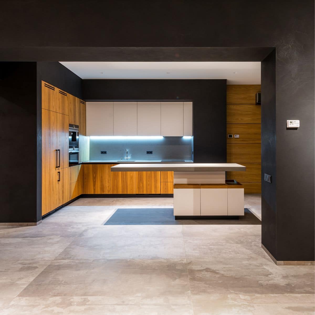 a black and brown hallway that leads to a kitchen