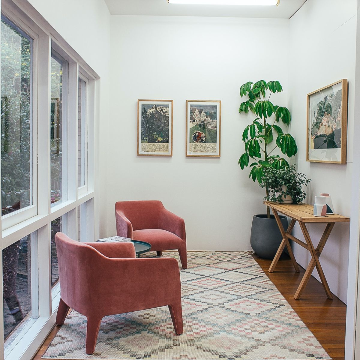 a hallway with wood floors, chairs, a plant, and a carpet