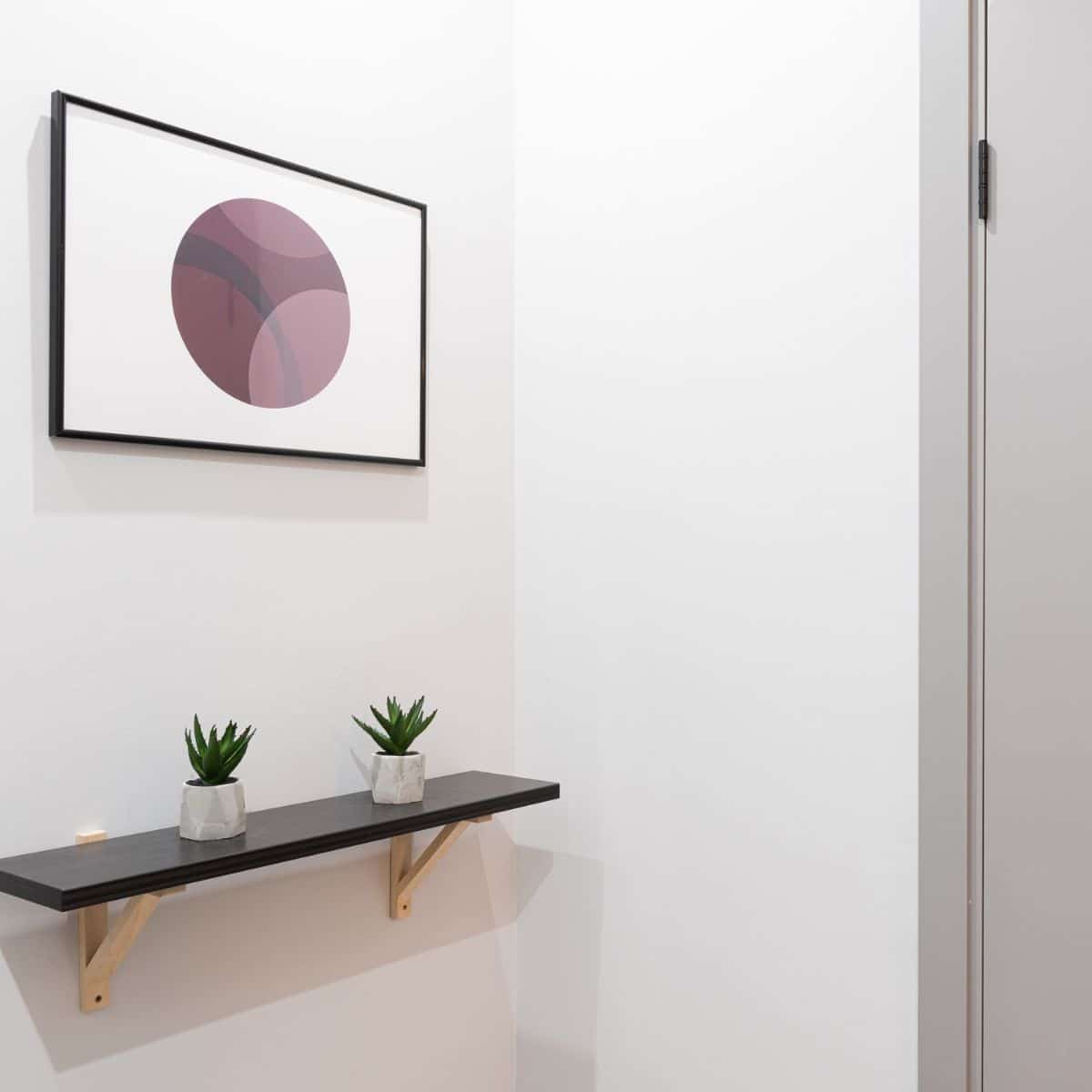 a picture frame and narrow shelf in a hallway