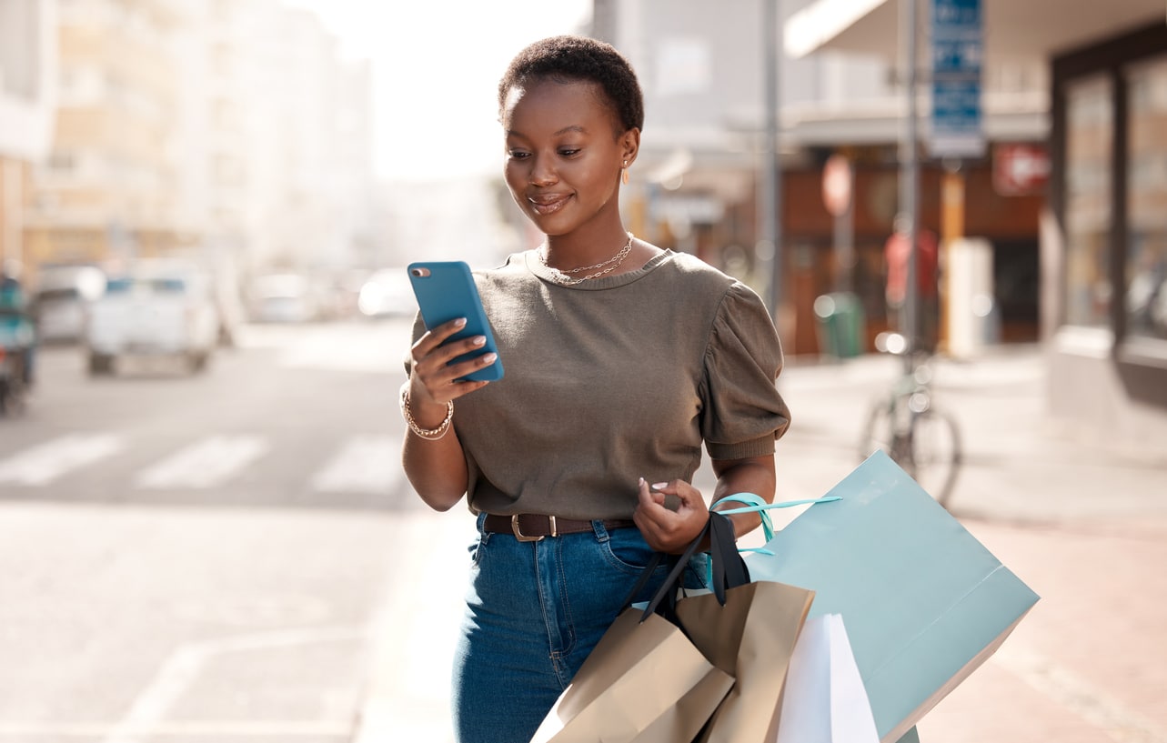 Woman using her cellphone outside while shopping in the city