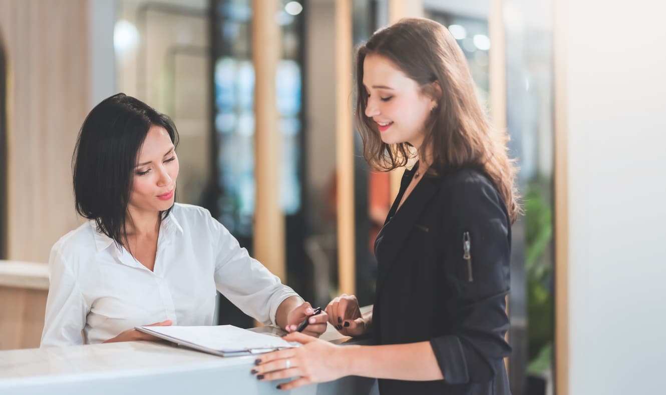 Receptionist woman showing rates of their services to female client at reception