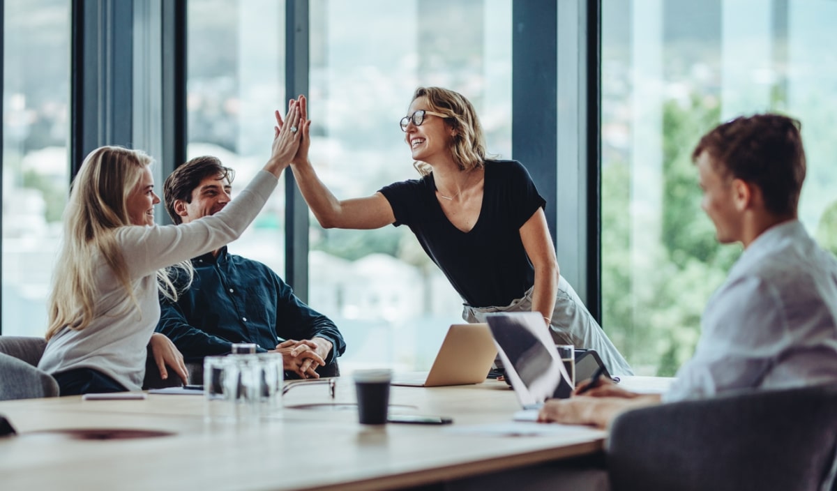 female professional giving a high five to her colleague in conference room