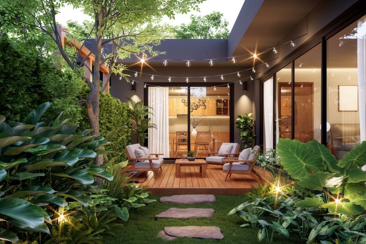 Modern contemporary courtyard with cosy seating and night lights, surrounded by lush greenery.