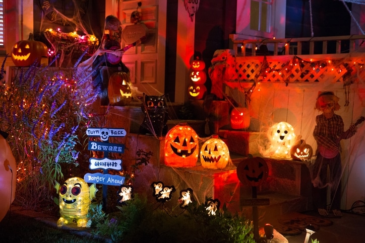 A house decorated with pumpkins, lights, and other spooky decor for Halloween.