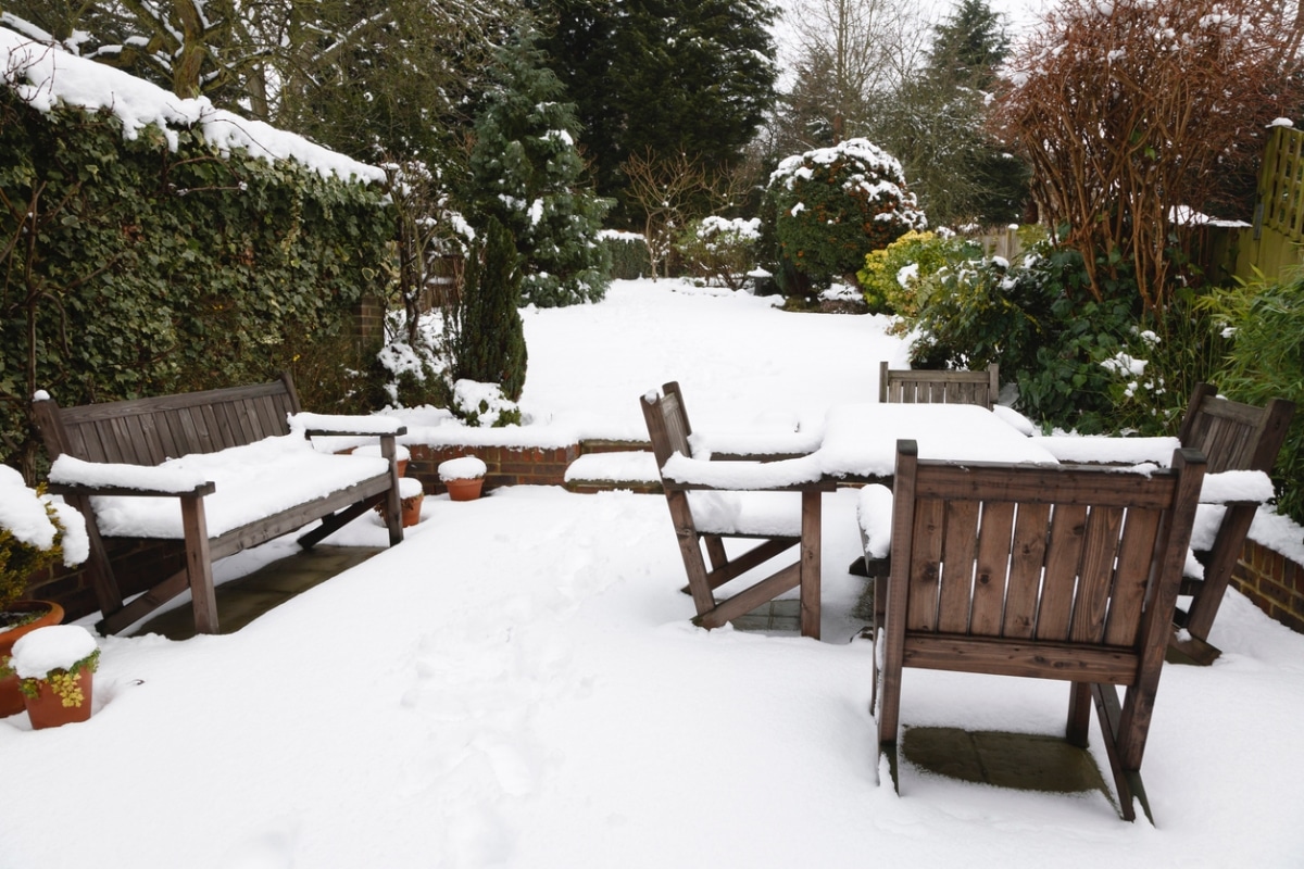 Wooden patio furniture covered in a thick layer of snow.